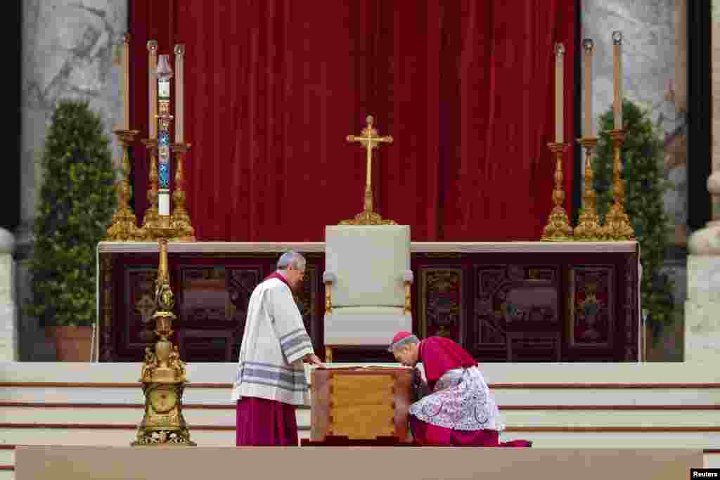 Archbishop Georg Gaenswein, right, kisses the Book of the Gospels on top of former Pope Benedict&#39;s coffin during his funeral, in St. Peter&#39;s Square at the Vatican, Jan. 5, 2023.&nbsp;