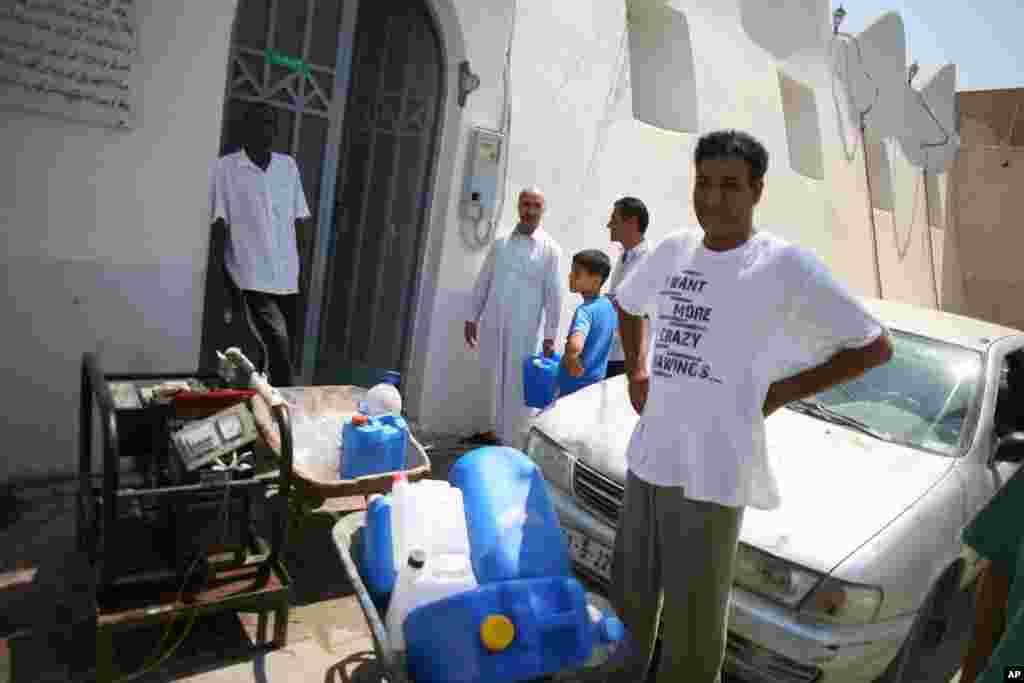 People gather outside a mosque where a generator pumps water from an inside well, August 27, 2011 (VOA - J. Weeks)