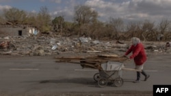 FILE - An elderly woman collects wood ahead of the winter in an area that was recently shelled in the village of Yasenove, south of the city of Pokrovsk, Donetsk region, on Oct. 8, 2024, amid the Russian invasion of Ukraine.