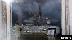 A member of the self-proclaimed Luhansk People's Republic (LNR) forces guides a tank to park after withdrawing it further from the frontline outside Luhansk, Ukraine, Oct. 3, 2015.