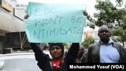 Protesters hold signs like this one, which demands an end to the intimidation of election officials, during a march in Nairobi, Aug. 1, 2017.