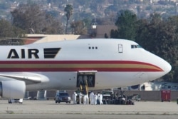 Personnel in protective clothing approach an aircraft, chartered by the U.S. State Department to evacuate Americans from Wuhan, China, after it arrived at March Air Reserve Base in Riverside County, California, Jan. 29, 2020.