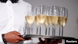 A man holds a tray of champagne flutes at the end of the A.F. Vandevorst Spring/Summer 2014 women's ready-to-wear fashion show during Paris fashion week Sept. 27, 2013.