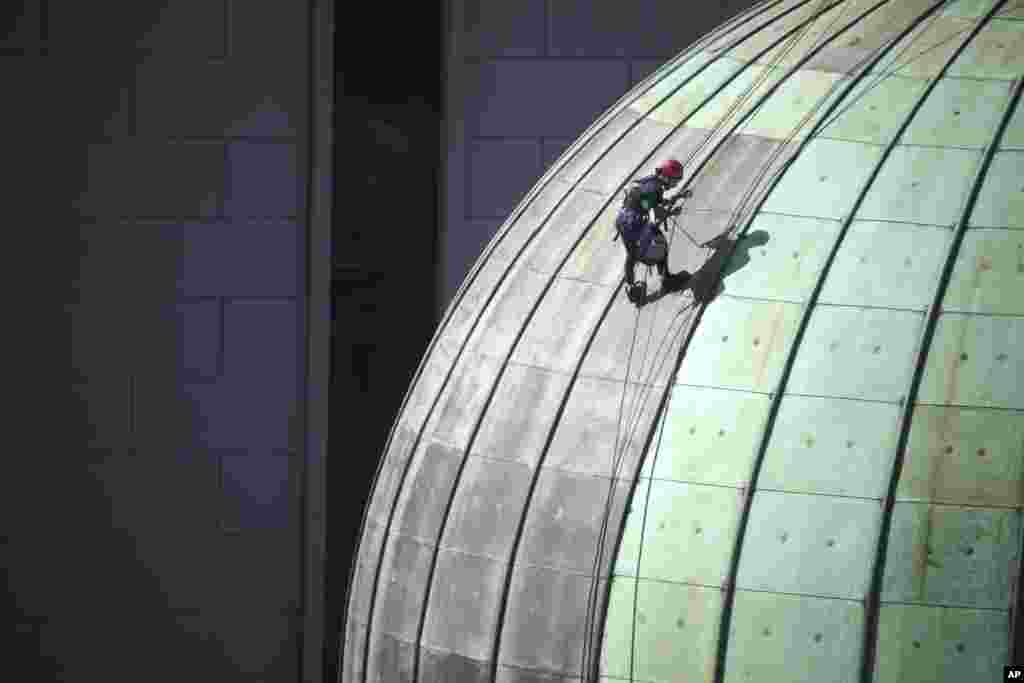 A man doing maintenance work abseils down the center dome on the Queen Victoria Building in Sydney, Australia.