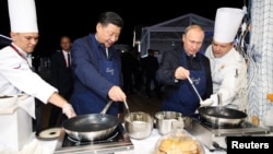 Presiden Rusia Vladimir Putin (kanan) dan Presiden China Xi Jinping memasak serabi (pancake) bersama dalam pertemuan bilateral di Vladivostok, Rusia (foto: ilustrasi). 