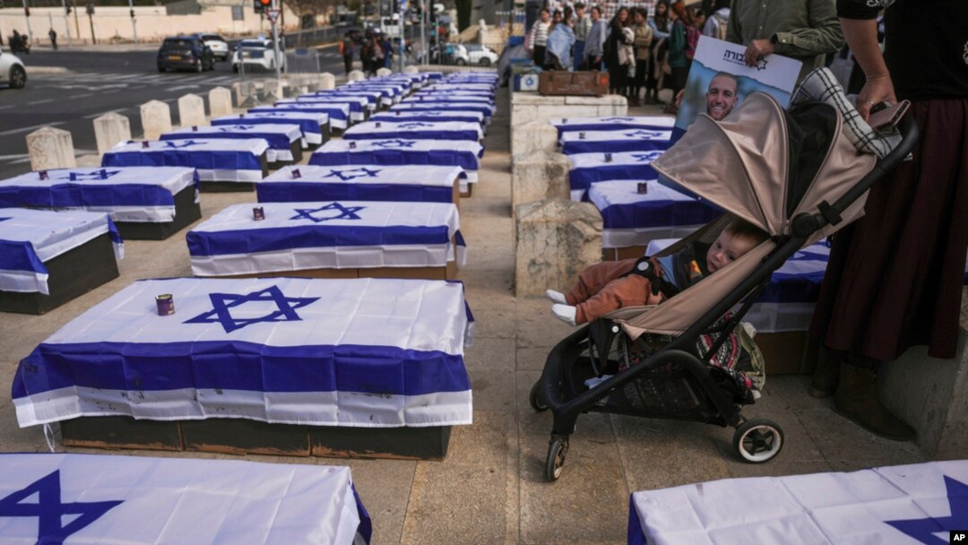 Para demonstran berdiri di dekat peti mati berbendera Israel sebagai simbol harga yang harus dibayar Israel karena menyetujui gencatan senjata dengan Hamas dalam demo menentang kesepakatan tersebut di Yerusalem pada 16 Januari 2025. (Foto: Ohad Zwigenberg/AP Photo)
