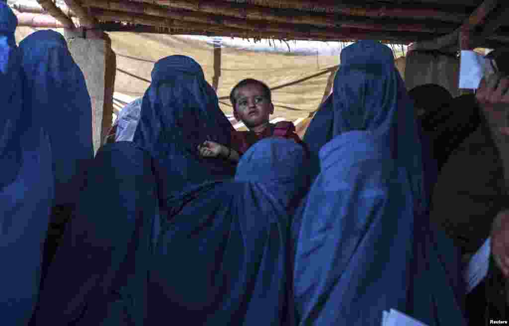 An Afghan woman holds a child as she waits with others to have a medical check-up at a health clinic set up by the UNHCR to mark World Refugee Day in Islamabad, June 20, 2014.