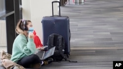 Katelyn Darrow gets some work done on her laptop as she waits to board her flight at the Philadelphia International Airport, Dec. 31, 2021, in Philadelphia. 