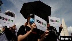 FILE - Protesters hold signs of the Hong Kong-Thailand-Taiwan network (Milk Tea Alliance) during a rally to demand that the government resign, that the parliament dissolve and that new elections be held, in Bangkok, Thailand, Aug. 16, 2020.