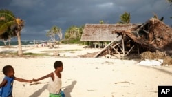 FILE - Children play on the beach in Takara, Efate Island, Vanuatu, May 30, 2015. The town was damaged months earlier during Cyclone Pam. Many people in the town considered rebuilding on higher ground to escape what they thought were the effects of climate change.