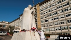 Una monja reza frente a la estatua del difunto Papa Juan Pablo II afuera del Hospital Gemelli, donde el Papa Francisco está ingresado para recibir tratamiento, en Roma, Italia, el 21 de febrero de 2025.