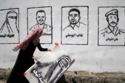 FILE - A Yemeni graffiti artist paints faces of victims of an al-Qaida militant attack on a wall during an "anti-terrorism" campaign in Sanaa, March 6, 2014.
