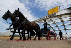 El ataúd del representante John Lewis es llevado sobre el puente Edmund Pettus en un carruaje tirado por caballos durante un servicio conmemorativo para Lewis, el domingo 26 de julio de 2020, en Selma, Alama.