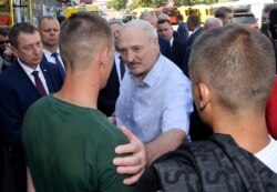 Belarusian President Alexander Lukashenko, center, speaks to an employee of the Minsk Tractor Wheel Plant in Minsk, Belarus, Aug. 17, 2020.