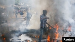 A resident tries to clear tires set afire during clashes between traders and police following demolitions of their homes and stalls near the Korogocho market in Nairobi, Kenya, May 8, 2020.