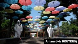 Para pekerja menyemprotkan cairan disinfektan untuk mencegah penularan virus corona (Covid-19) di Solo, Jawa Tengah, 18 Juni 2020. (Foto: Antara via Reuters)