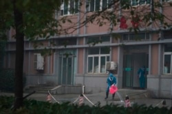 Hospital staff wash the emergency entrance of Wuhan Medical Treatment Center, where some infected with a new virus are being treated, in Wuhan, China, Jan. 22, 2020.