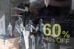 Workers wearing protective gear are reflected in a window of a store as they prepare to spray disinfectant as a precaution against the coronavirus in a shopping district in Seoul, South Korea, Feb. 27, 2020.