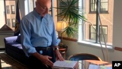 FILE -- Mark Robbins, the last remaining member of the Merit Systems Protection Board, looks through stacks of legal cases piled up on his desk in Washington office, Aug. 7, 2018. 