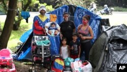 Nelson Martínez, izquierda, su esposa Makelys Faneite, centro, y su hermana Maryuri Alvarez, posan para una foto con sus hijos afuera de su carpa en un parque donde vivían con otros migrantes venezolanos desempleados, en Bogotá, en junio de 2020. 