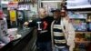 FILE - Robert, a migrant from Ghana, stands with his employer Massimiliano in a bar in Riace, Calabria region, Italy, Nov. 22, 2013.