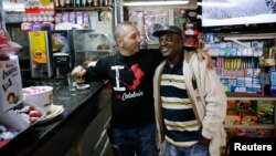 FILE - Robert, a migrant from Ghana, stands with his employer Massimiliano in a bar in Riace, Calabria region, Italy, Nov. 22, 2013.