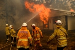 FILE - Firefighters battle the Morton Fire as it burns a home near Bundanoon, New South Wales, Australia, Jan. 23, 2020.