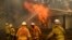 FILE - Firefighters battle the Morton Fire as it burns a home near Bundanoon, New South Wales, Australia, Jan. 23, 2020. 