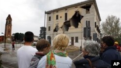 Warga tengah mengamati bangunan balai kota St.Agostino yang rusak akibat gempa (20/5). Gempa berkekuatan 6.0 mengguncang sekitar wilayah Bologna, menewaskan sedikitnya empat orang dan merusakkan bangunan serta rumah tinggal penduduk setempat.