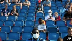 FILE - Spectators, some with face masks, watch a soccer match in Le Havre, western France, July 12, 2020.