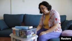 FILE - Leticia de Souza Soares, who suffers from pain and health problems caused by long COVID-19, sits next to the medicines she uses in her home, in Salvador, Brazil, Dec. 8, 2023.