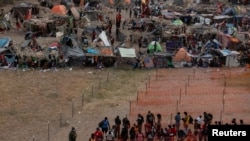 Migrantes esperan ser procesados en un campamento improvisado a lo largo del Puente Internacional en Del Rio, Texas, EE. UU., el 21 de septiembre de 2021.