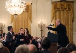 FILE - A White House staff member reaches for the microphone held by CNN's Jim Acosta as he questions U.S. President Donald Trump during a news conference at the White House in Washington, Nov. 7, 2018.