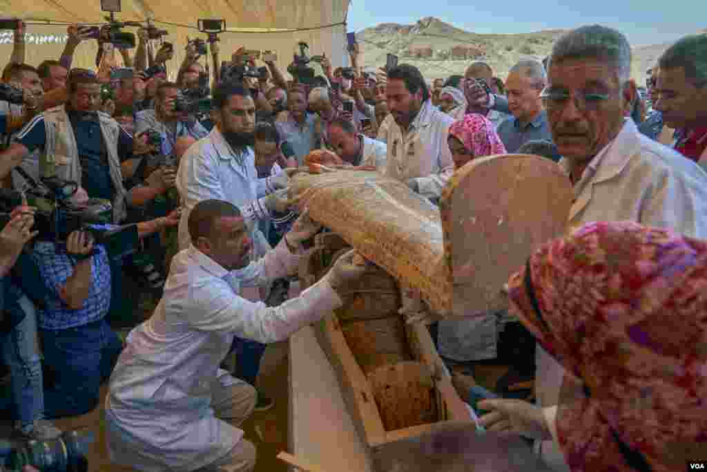 Restorers remove the coffin&#39;s cover to reveal the female mummy wrapped in linen and talismans to guide her in the afterlife. (H. Elrasam/VOA)