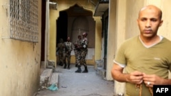 A resident looks on as Comoros armed forces members search and patrol the medina for weapons and armed men at Mutsamudu, Oct. 20, 2018, on the island of Anjouan.