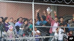 Migrantes centroamericanos esperan comida en El Paso, Texas, el miércoles 27 de marzo de 2019, en una celda de alambre erigida por la Oficina de Aduanas y Protección Fronteriza de EE.UU. para procesar una oleada de familias migrantes y menores no acompañados. 