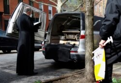 Monsignor Kieran Harrington, Vicar for Communications for the Diocese of Brooklyn, prays over the body of the Rev. Jorge Ortiz-Garay in the Brooklyn borough of New York as they prepare to transport his body to JFK International Airport, May 3, 2020.