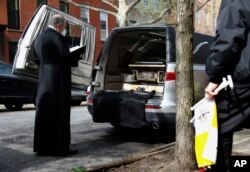 Monsignor Kieran Harrington, Vicar for Communications for the Diocese of Brooklyn, prays over the body of the Rev. Jorge Ortiz-Garay in the Brooklyn borough of New York as they prepare to transport his body to JFK International Airport, May 3, 2020.