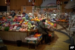 FILE - Vendors wait for customers at their fruit market stall in downtown Kyiv, Ukraine, Monday, Feb. 14, 2022. With so many refugees, businesses worry they will not have enough customers even after the war ends. (AP Photo/Emilio Morenatti, File)