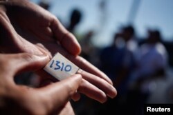 Un solicitante de asilo venezolano muestra su número de cola dado por ellos mismos según el orden en que llegaron, mientras acampa cerca de la frontera, en Nuevo Laredo, México, 27 de junio de 2023. REUTERS/ Daniel Becerril