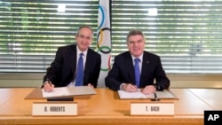 Chủ tịch IOC Thomas Bach (phải) và CEO của tập đoàn Comcast Brian L. Roberts tại buổi ký thỏa thuận bảo đảm quyền phát sóng Olympic ở Mỹ.