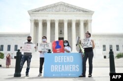 FILE - Deferred Action for Childhood Arrivals (DACA) demonstrators stand outside the U.S. Supreme Court in Washington, June 15, 2020.