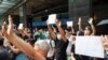 FILE - Supporters raise white paper to avoid slogans banned under the national security law as they support arrested anti-law protester outside Eastern court in Hong Kong, China, July 3, 2020.