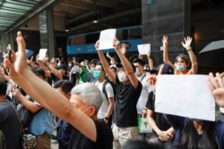 FILE - Supporters raise white paper to avoid slogans banned under the national security law as they support arrested anti-law protester outside Eastern court in Hong Kong, China, July 3, 2020.