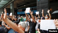 FILE - Supporters raise white paper to avoid slogans banned under the national security law as they support arrested anti-law protester outside Eastern court in Hong Kong, China, July 3, 2020.