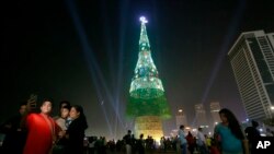 A Sri Lankan family takes photographs standing near an enormous artificial Christmas tree as others gather in Colombo, Sri Lanka, Dec. 24, 2016. Sri Lanka has unveiled a towering Christmas tree, claiming to have surpassed the world record for the tallest 