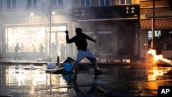 Rioters throw stones toward a police office in the Belgium capital, Brussels, Wednesday, Jan. 13, 2021.