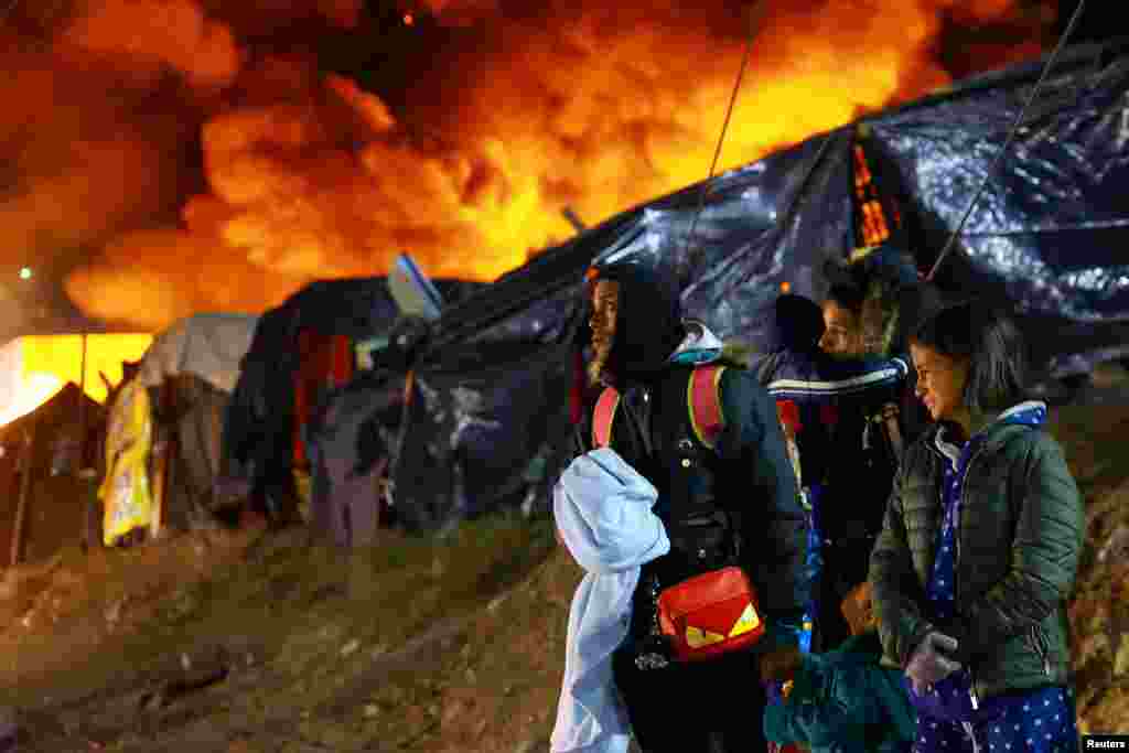 Migrants react during an eviction operation carried out by Mexican authorities, while the makeshift camp where they lived catches fire, in Chihuahua, Chihuahua state, Mexico, Jan. 18, 2025. 