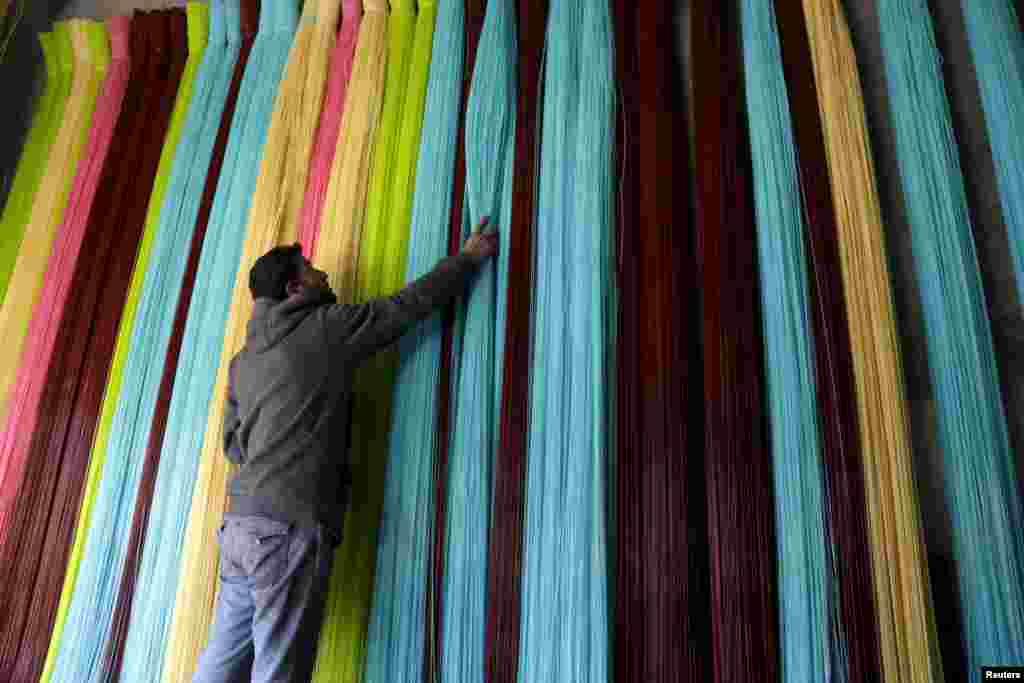 A man adjusts plastic strings, used to produce mats, inside a mat factory in the rebel-controlled area of Maarshureen town in Idlib province, Syria.