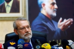 Iranian parliament speaker Ali Larijani attends a news conference at the Iranian embassy in Beirut's southern suburbs, as a picture of late Iran's Quds Force top commander Qassem Soleimani is seen in the background, Feb. 17, 2020.